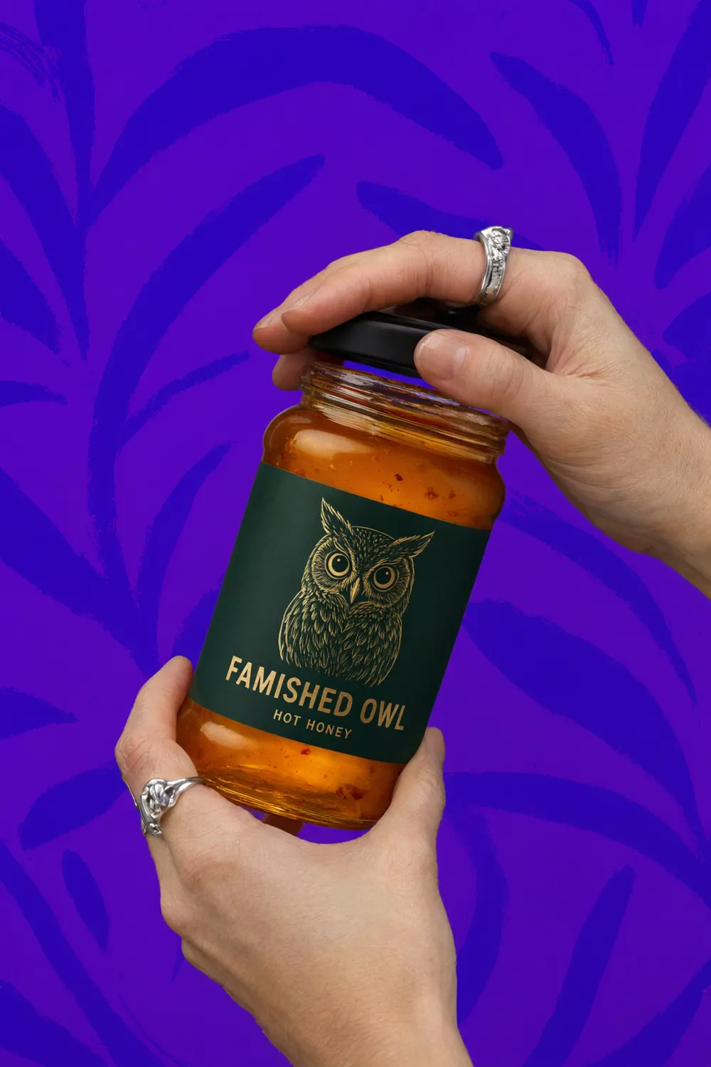 Two hands twisting the lid off a jar of hot honey